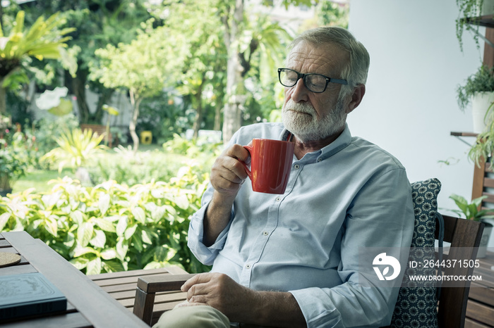 senior man happiness sitting and holding cup of coffee at balcony near garden at nursing home for relaxing