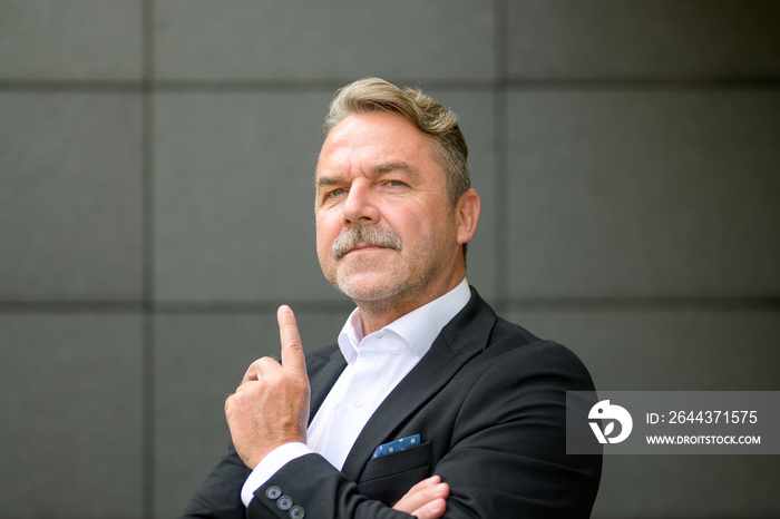 Confident middle aged businessman pointing upwards with finger