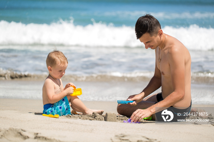 father and son building sand castle on beach