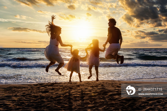 Glückliche Familie im Urlaub springt vor Freude am Strand während des Sonnenunterganges in die Luft