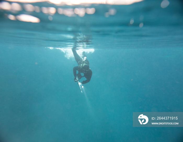 Spearfishing man with flashlight at the top of lake