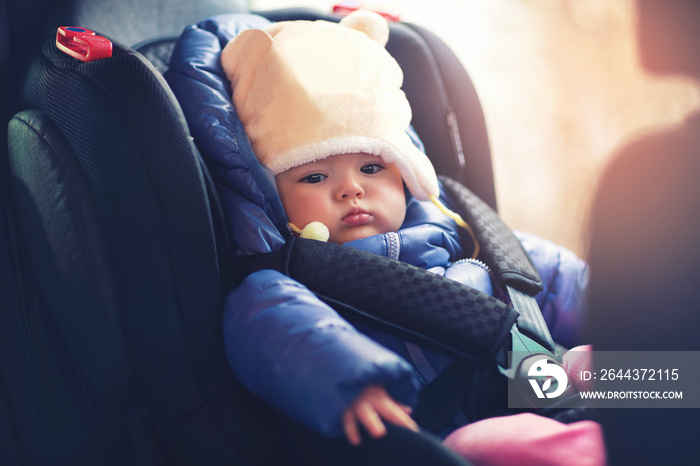 Adorable little girl sitting in car in winter clothes