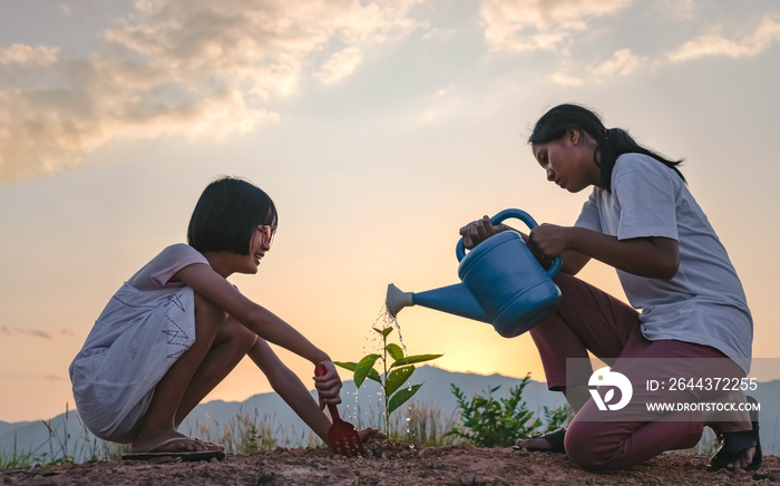 Silhouette two children planting at sunset.Concept of world environment day.