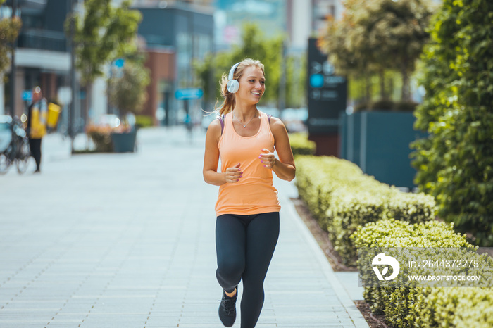 Woman running. Female runner jogging, training for marathon. Fit girl fitness athlete model exercising outdoor. Photo of young woman running on sidewalk in morning. Health conscious concept