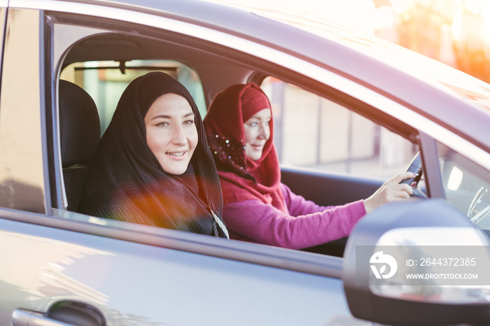 Two smiling muslim women inside a car