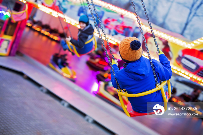 Child, cute boy riding chain swing carousel on sunset, motion blur