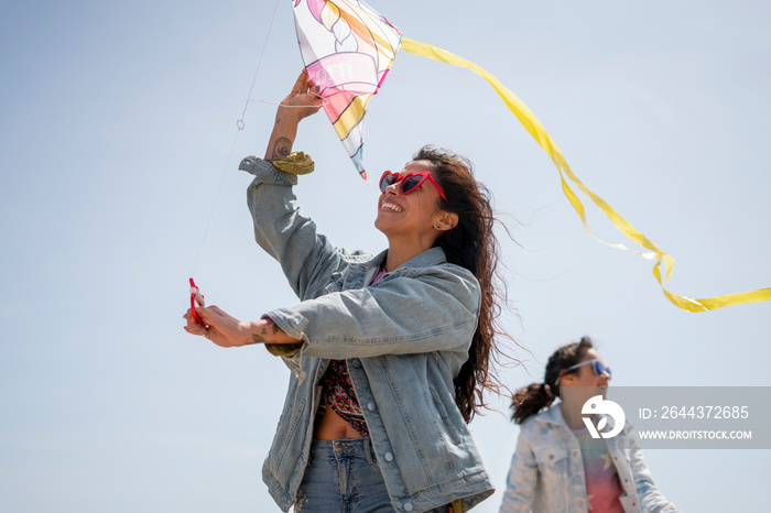 Mother and daughter (8-9) flying kite on beach