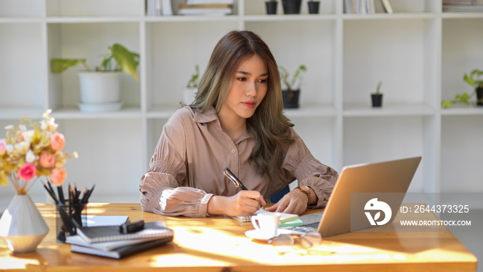 Female university student taking an online class, lecturing on her notepad