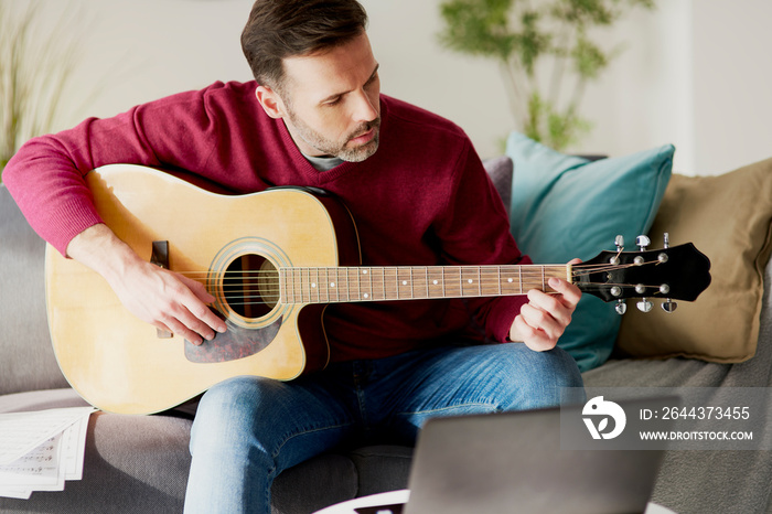 Mid age man playing an acoustic guitar