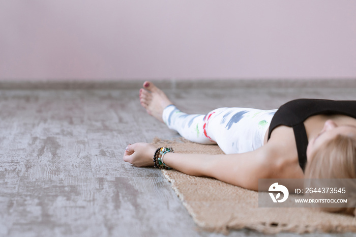 Adult woman meditating in savasana pose on bamboo yoga mat after working out at home and doing yoga exercise. Shavasana Posture, meditation, resting after practice, breathing.