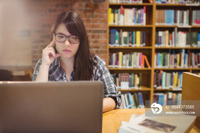 Thoughtful female student using laptop