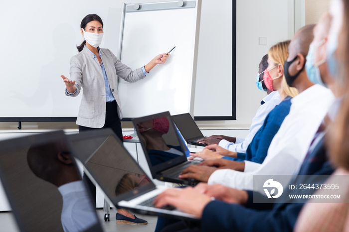 Side view of a group of businessmen in protective masks undergoing training under the guidance of a teacher