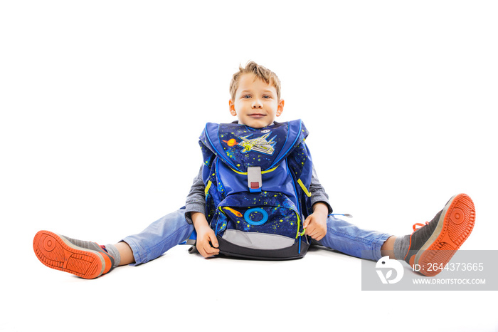 Child with backpack sits on the floor - isolated