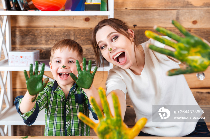 Little boy and mother showing hands painted in colorful paints