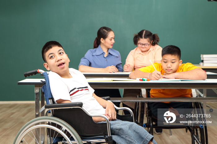 Asian disabled children Or, an autistic child learns to read, write and train their hand and finger muscles with a teacher at their classroom desk.