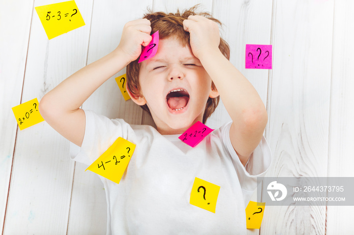 Crying child with question symbol with stickers on his head and around.