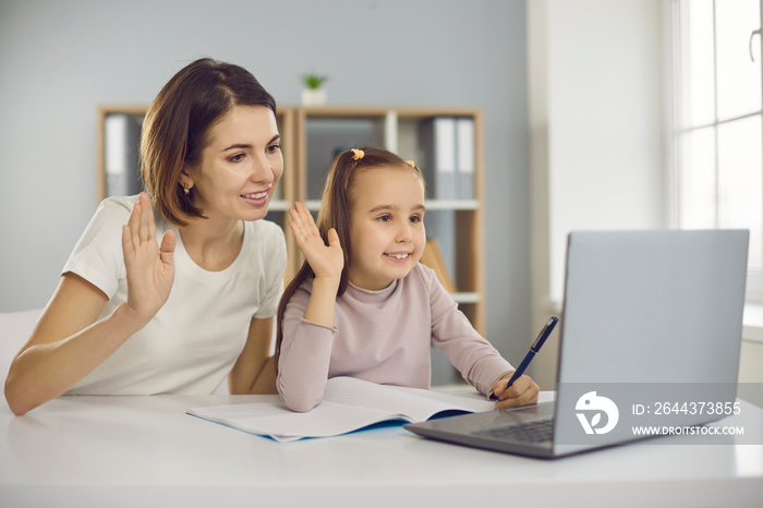 Family staying at home and E-learning via interactive platform. Happy smiling mother and child waving hands at laptop computer, greeting school teacher or private tutor in online lesson via video call