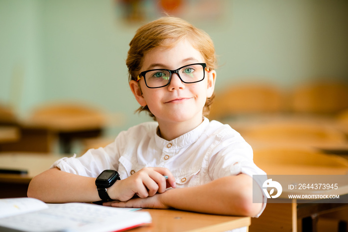 cute blonde school student with stylish glasses writing in classroom