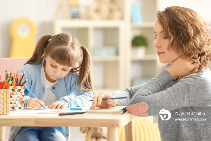 Female psychologist with cute little girl during art therapy