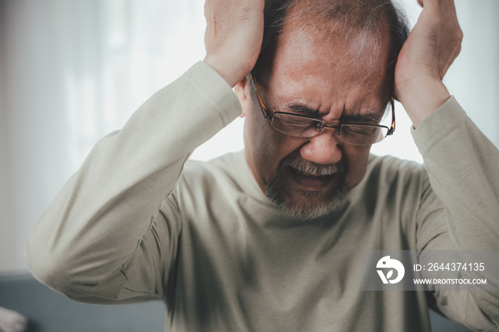 Headache. Close up of elderly holds head with hand suffering from migraine headache, Sad Asian senior man sitting on sofa feeling hurt and lonely at home, Old age health problems, healthcare