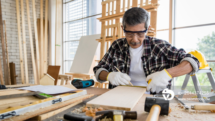 Senior carpenter making marks on wooden board