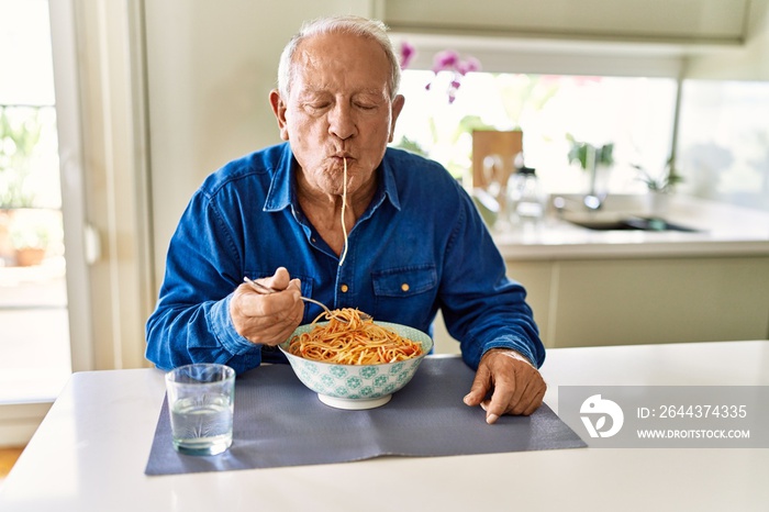 Senior man eating spaghetti at kitchen