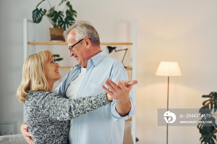 Dancing in the domestic room. Senior man and woman is together at home