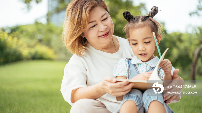 Grandmother and grand daughter enjoying sunny garden holiday together, outdoors space, leisure lifestyle,happy teaching with flare light sky in park.