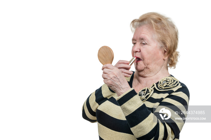 Old woman applying red lipstick doing make-up isolated on white background