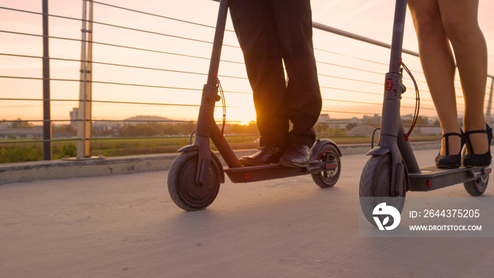 LENS FLARE: Co-workers in formal wear ride electric scooters to work at sunrise.