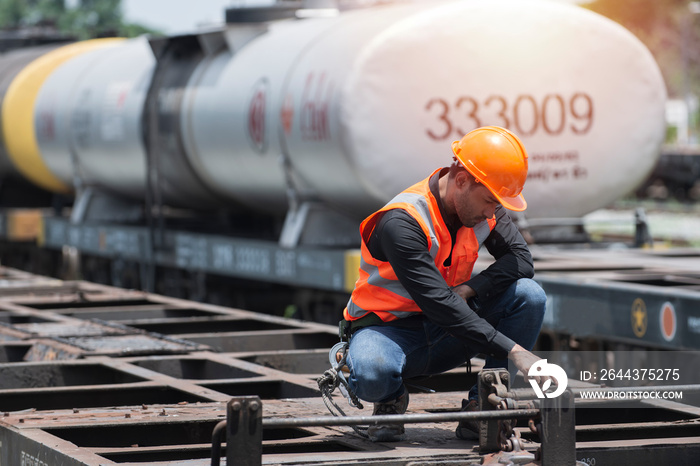 worker on the station. worker on the railway. worker sitting on bogie with oil tank on background.