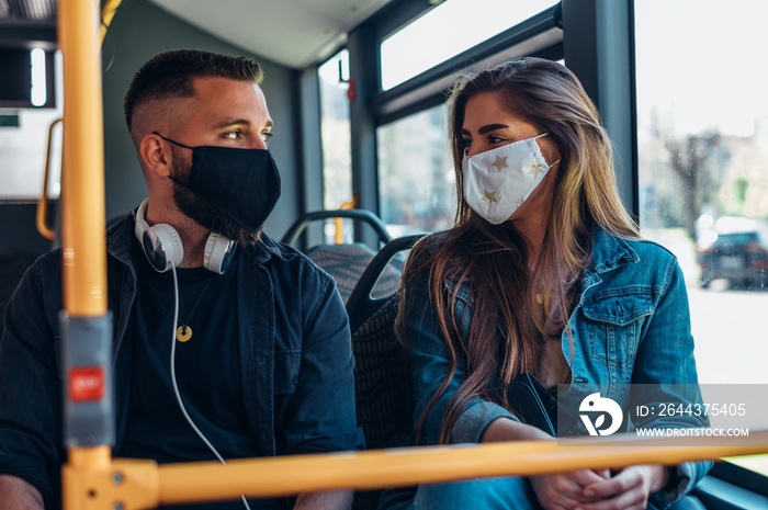 Young couple wearing protective masks riding a bus