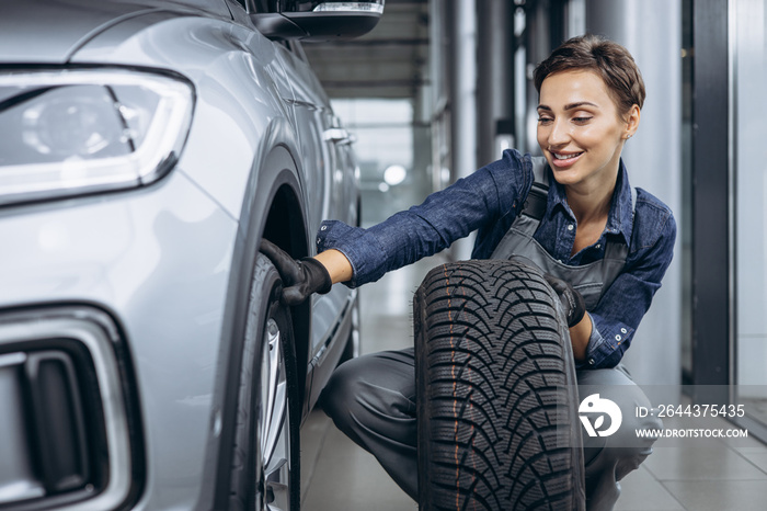 Woman car mechanic changing tires at car service