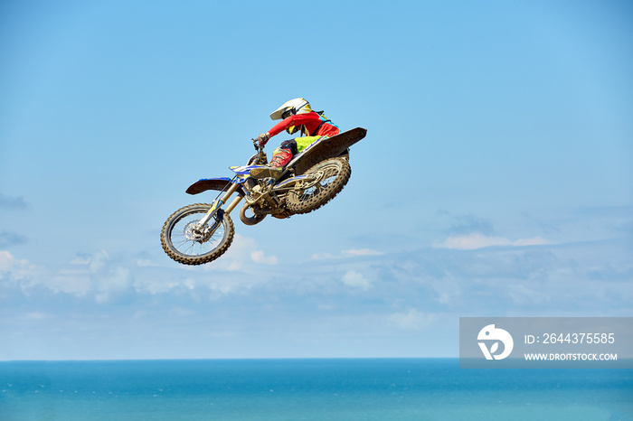 Biker does the trick and jumps in the air. Extreme concept, adrenaline. Copy space. Sky background