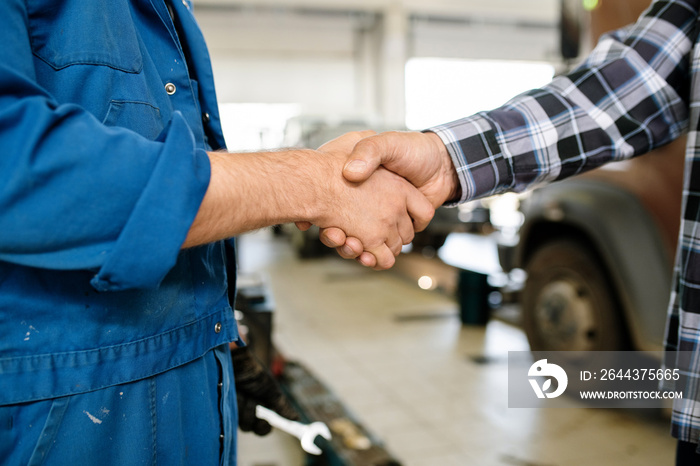 Handshake of technician of car repair service in workwear and one of clients