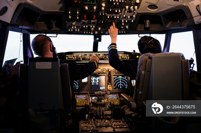 Captain and woman copilot getting ready to fly airplane and takeoff with dashboard navigation in cockpit command. Airline crew fixing altitude level and with control panel buttons, flying plane.