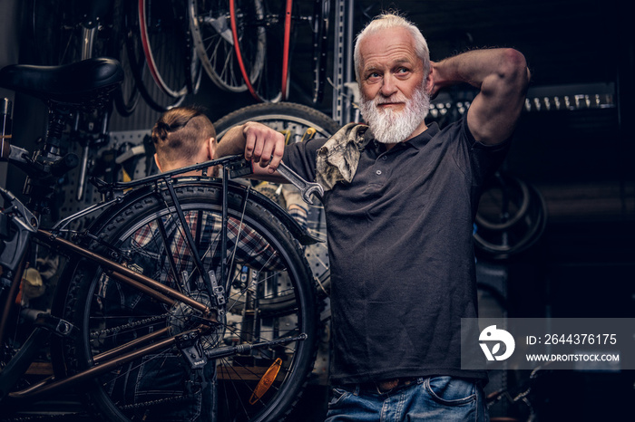 Aged man mechanic repairing bicycles indoors his workshop