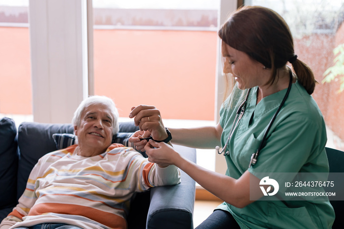 smartwatch for seniors - nurse puts a gadget on the wrist of an elderly person for monitoring and assistance