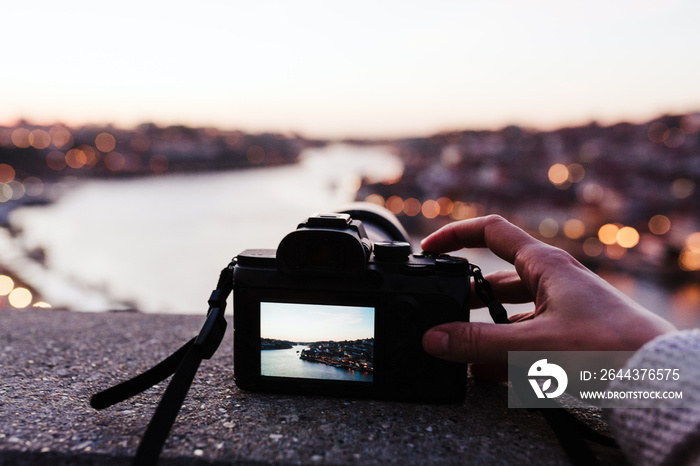 close up of woman in Porto bridge taking pictures with camera at sunset. Tourism in city Europe