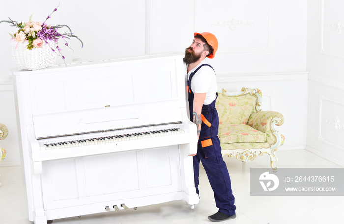 Guy from transportation company moving old piano alone. Tired guy lifting heavy stuff