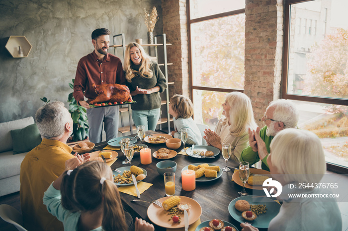 Photo of full family reunion sit feast dishes table meet big roasted turkey ovations clap hands multi-generation eight relatives annual event in living room indoors