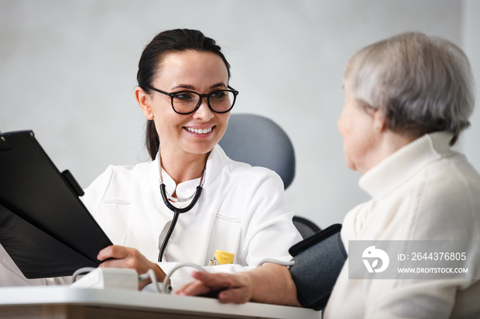 healthcare in hospital. smiling female doctor with clipboard consulting senior lady patient after treatment in medical clinic cabinet