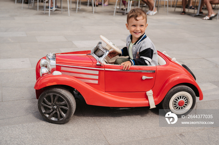 A little boy poses in a mini racing car. Play and relax in the fresh air.