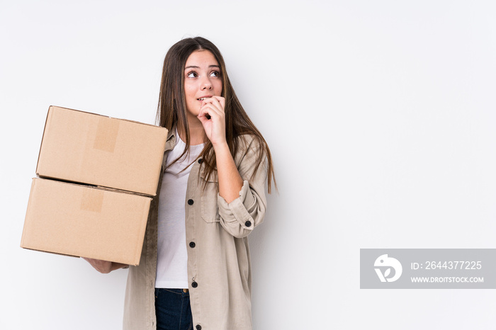 Young caucasian woman moving to a new home relaxed thinking about something looking at a copy space.