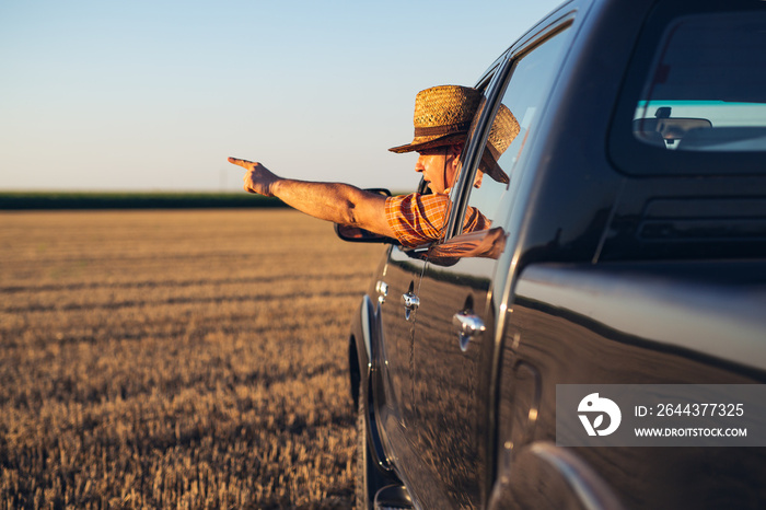 Young man in straw hat driving truck. Life on a farm.