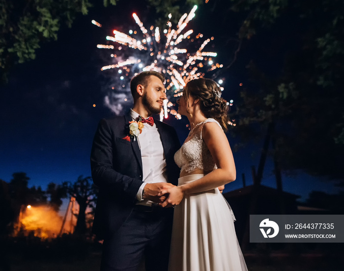 Wedding fireworks. Bride and groom hugging in the night on firework and salute background on night sky, enjoying the happiest day in life .