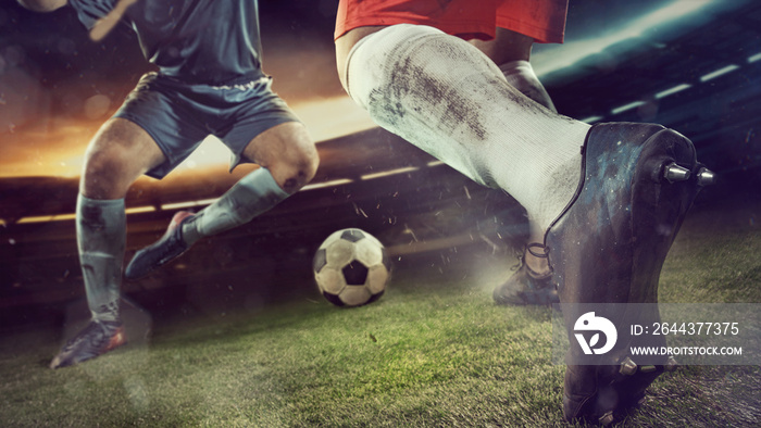 Two male soccer, football players dribbling ball at the stadium during sport match on dark sky background.