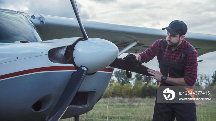 Aircraft mechanic polishing plane and then standing satisfied with his job.