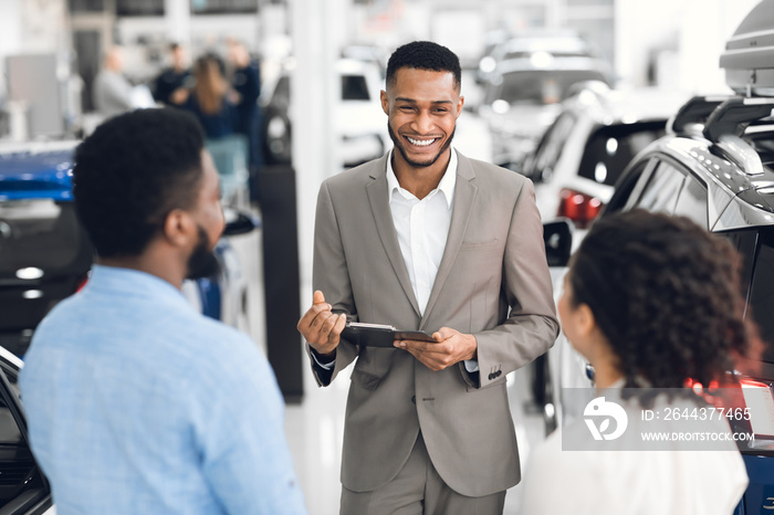 Professional Dealer Talking With Customers Showing Automobiles In Dealership Store