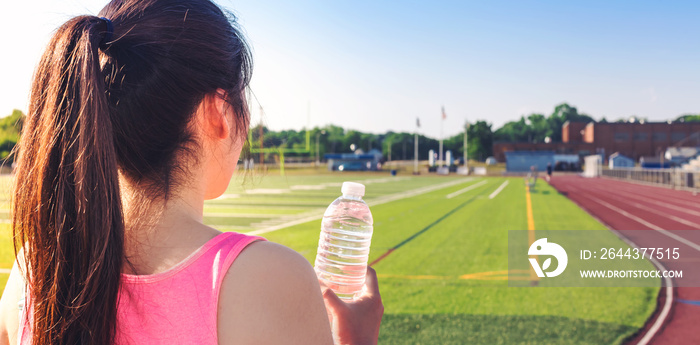 Female athlete drinking water on a running track